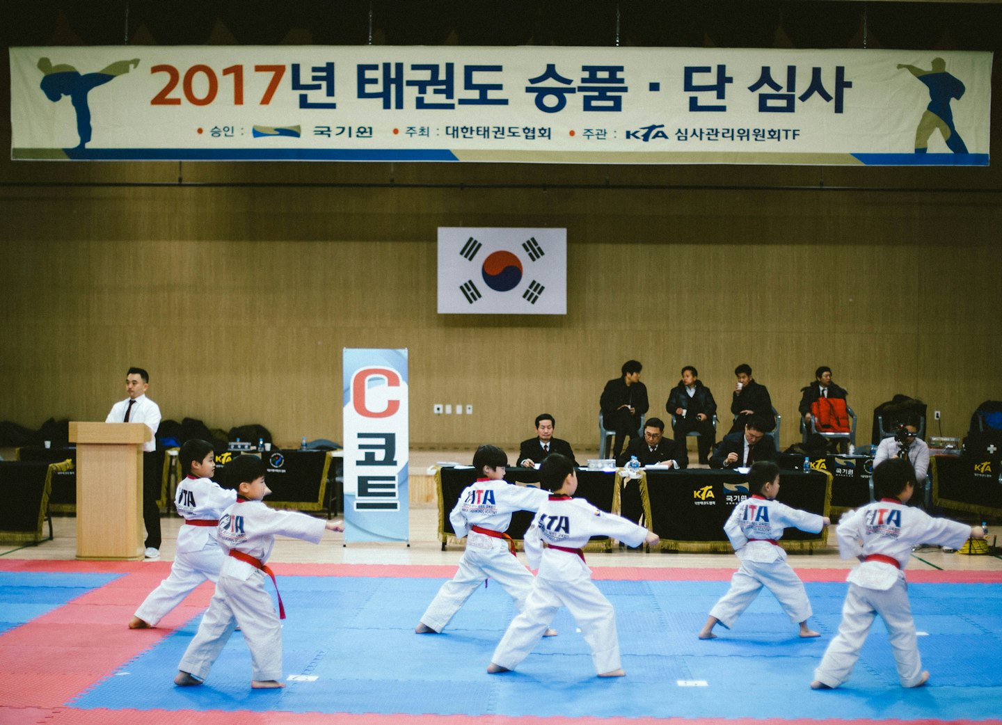 Children in taekwondo uniforms perform a synchronized martial arts pose.